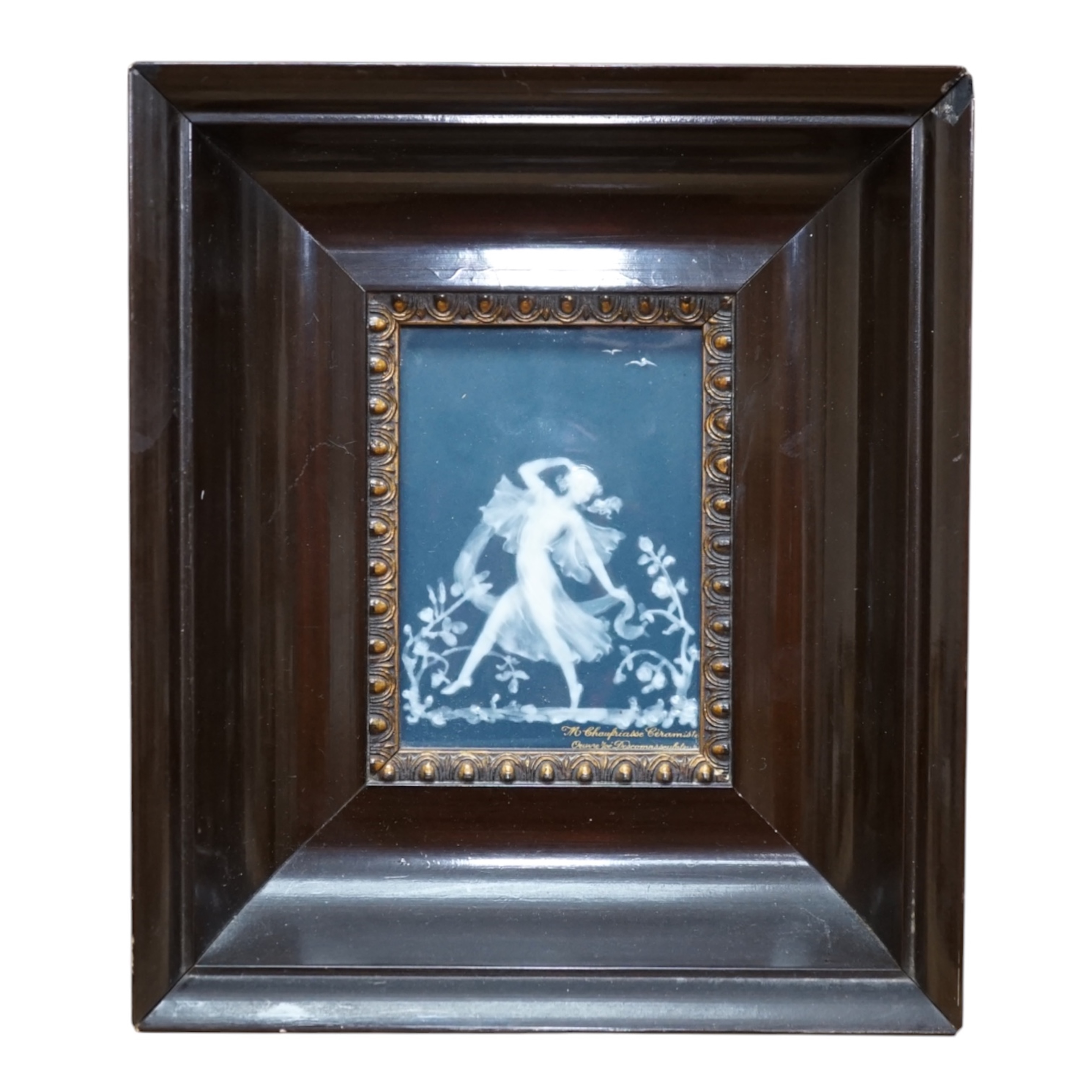 A framed Limoges blue and white pate-sur-pate plaque of a dancing fairy, signed Descomps, plaque 7cm x 10cm. Condition - good